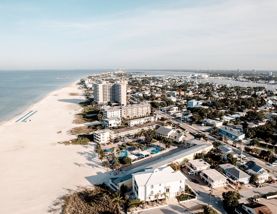 An aerial view of a coastal city with buildings close to a wide sandy beach and the ocean.